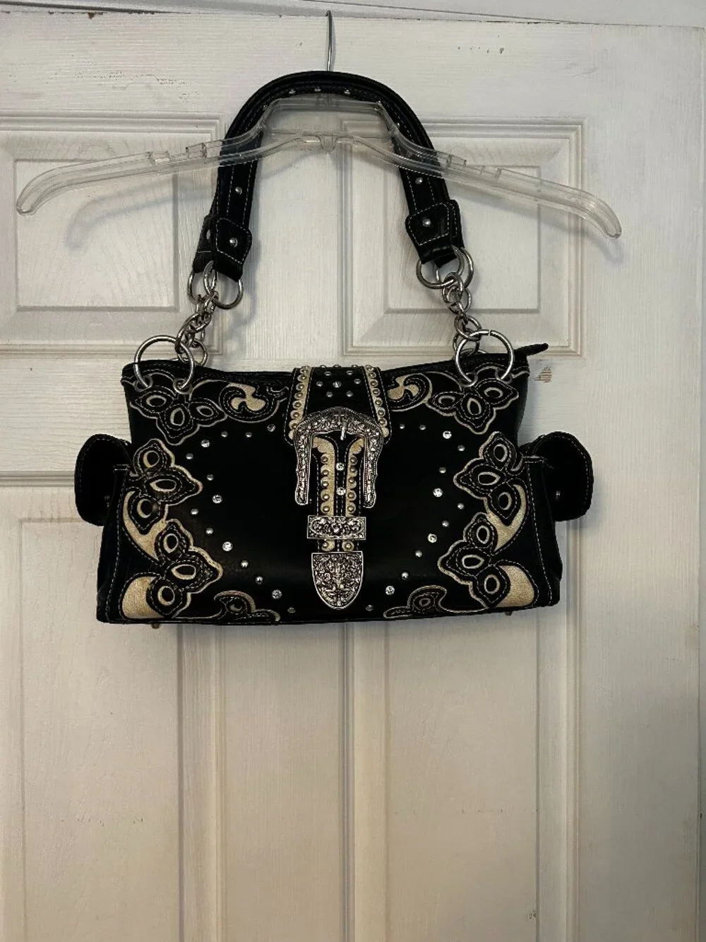 Stylish black and white western‑style satchel featuring decorative tooling, crys